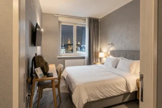 Chambre moderne et épurée d'un hôtel économique près de la gare de Strasbourg, avec lit double en draps blancs et bagage de voyage posé sur le bureau