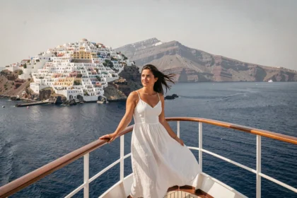 Femme sur le pont d'un bateau de croisière approchant la caldeira de Santorin avec vue sur les maisons blanches d'Oia