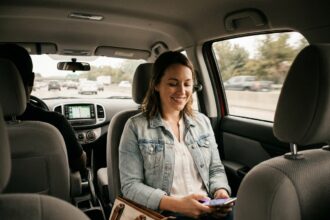 Passagère souriante dans une voiture de covoiturage consultant son smartphone pendant un trajet sur autoroute