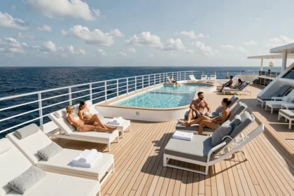 Pont extérieur d'un navire de croisière Virgin Voyages avec piscine et passagers adultes se relaxant en mer